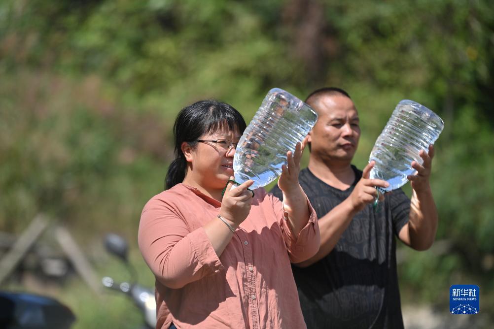 楊寧（左）在查看村民剛剛采集的水樣，為山泉水引水工程做準(zhǔn)備（10月8日攝）。新華社記者 黃孝邦 攝